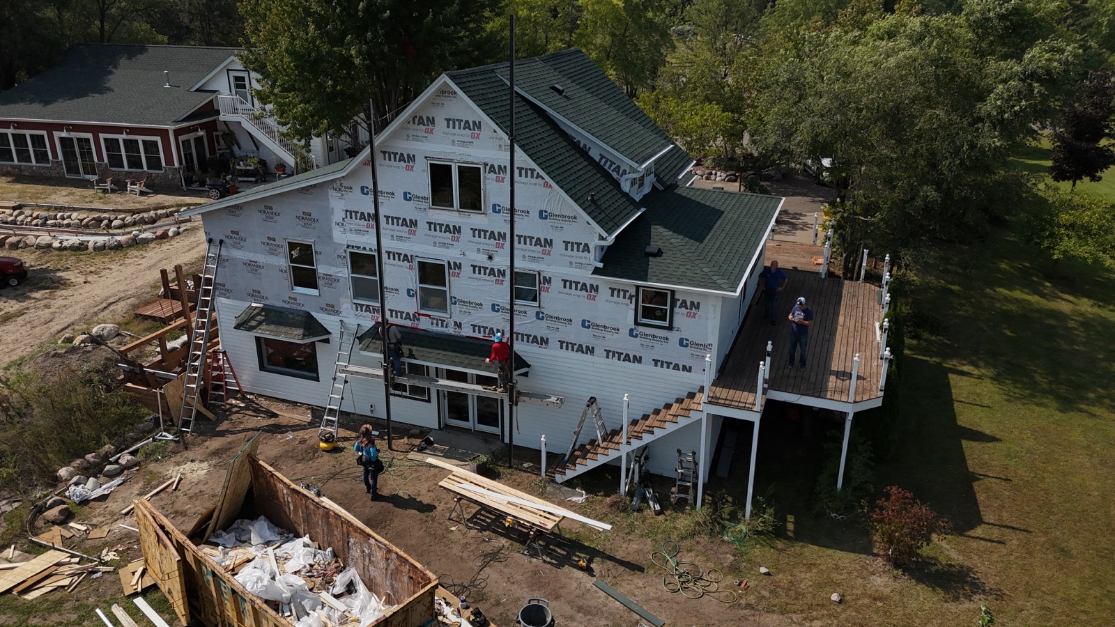House exterior during construction with housewrap, installed windows and unfinished exterior work.