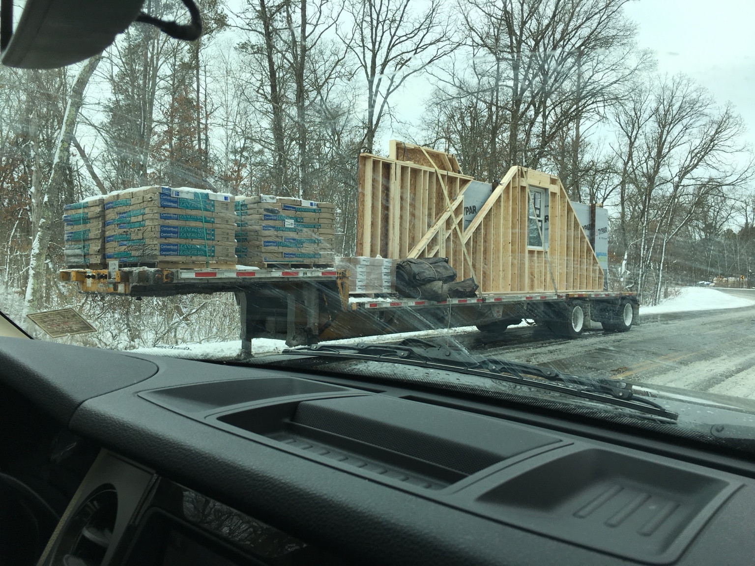 Prefabricated wall panels and packaged roofing materials on a delivery trailer.