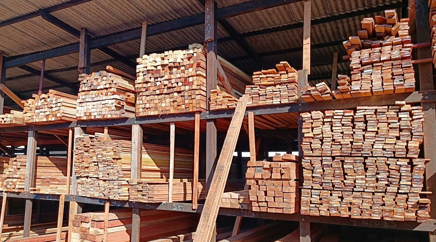 Stacks of lumber stored on racks beneath a roof.