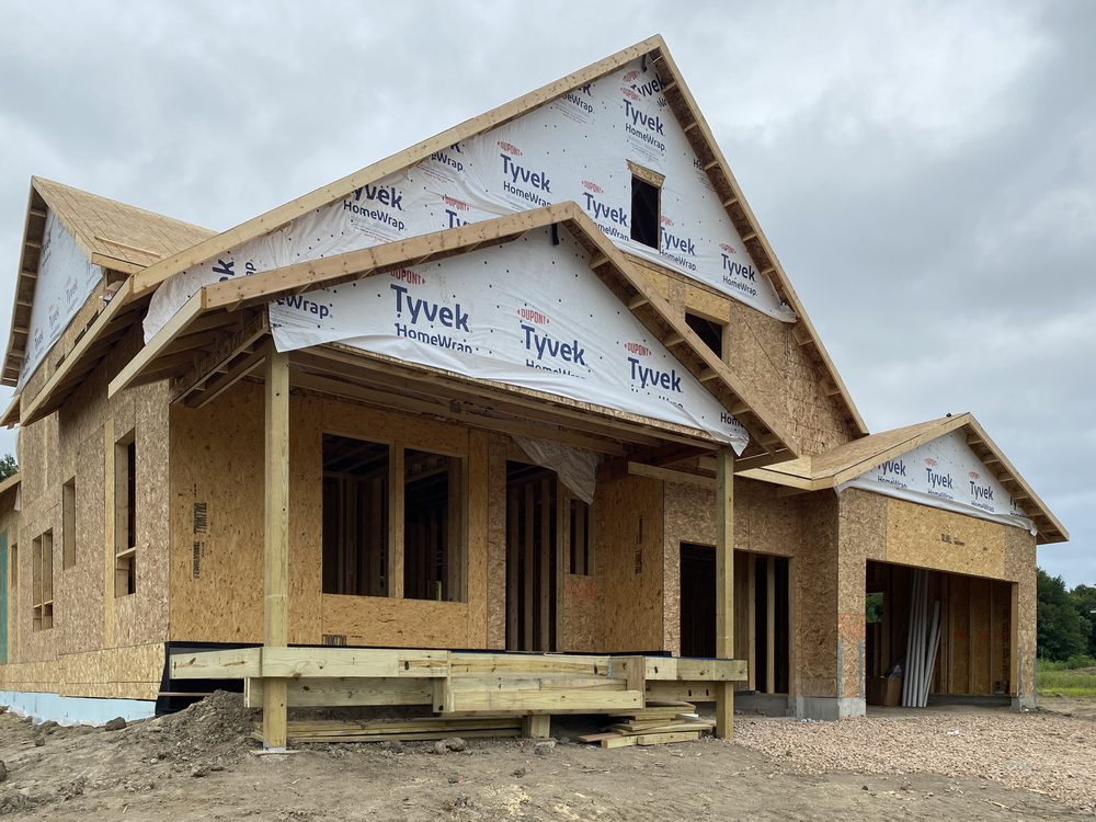 A framed and sheathed house with gables and porch posts.